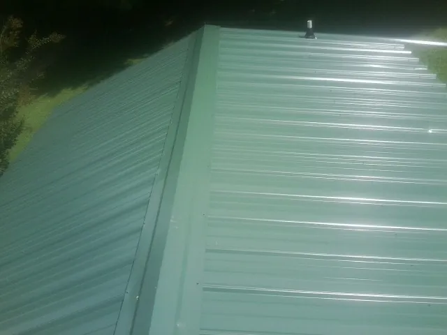 New green metal panels meeting at the ridge of a roof — Flat Roof Repair work by our crew in East Chicago