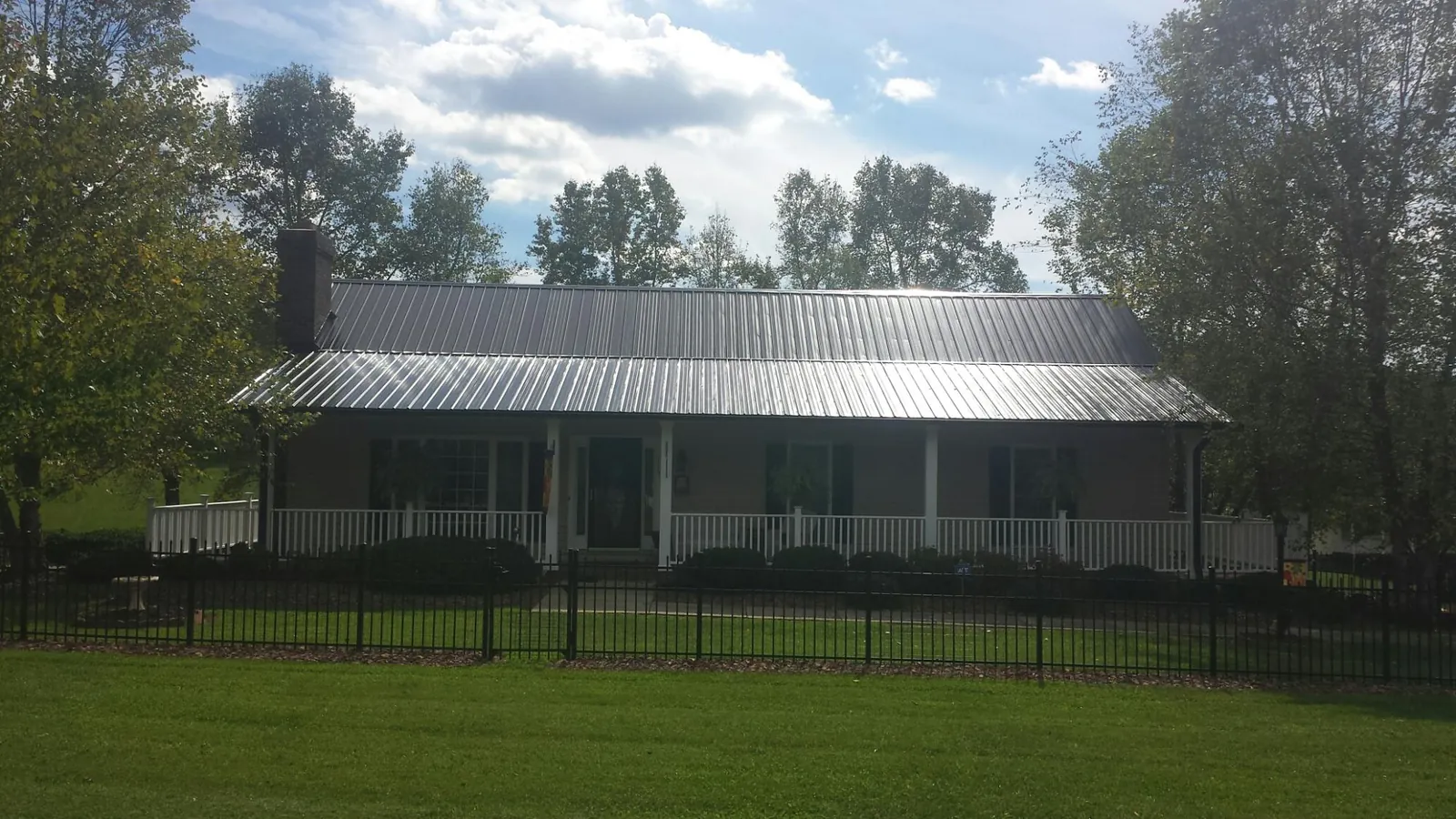 Gray metal roof on a brick ranch with a full width front porch — Gutter Guard Installation work by our crew in East Chicago