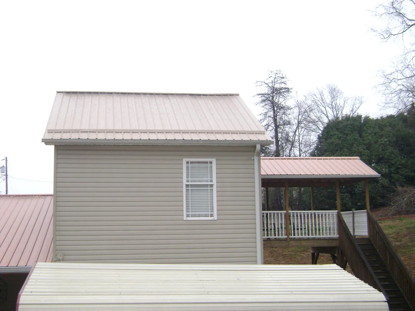Tan metal roofs on a two story addition and attached porch, from a Roof Replacement job in East Chicago