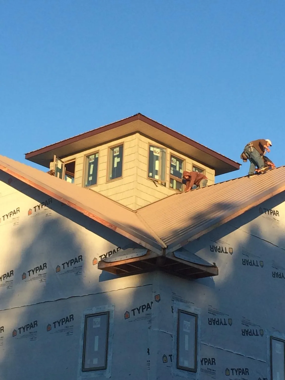 Roofers working around a rooftop cupola on a new metal roof at sunset — Roof Waterproofing in East Chicago by Roofing Brothers